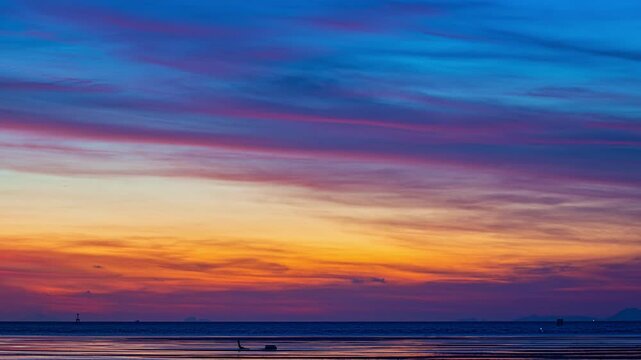 Time lapse amazing sky at twilight over the shallow sea.
Villagers go out to collect shellfish during low tide. 
A striking seascape capturing the vivid hues of sky blending colors over the ocean