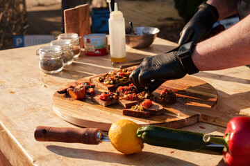 Grill master preparing bread with grilled vegetables and meat at a grill party