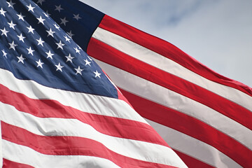 Obraz premium Close up full frame of United States of America flag flying in the wind with blue sky background