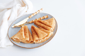 Golden crepes on white wooden table. Pancake day, Maslenitsa. Top view