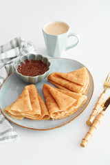 Crepes with chocolate cream and coffee on white wooden table. Pancake day, Maslenitsa