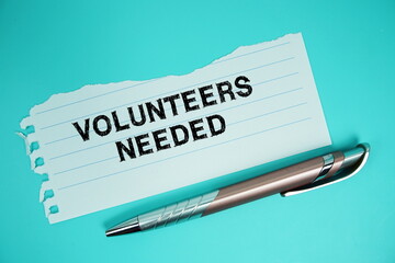 Volunteers Needed text written on paper with pen flat lay on green background