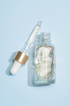 Skincare serum bottle with 24 k gold flecks on blue background
