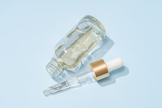 Serum bottle with 24 k gold flakes and dropper on blue background