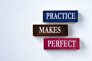 PRACTICE MAKES PERFECT - words on colorful wooden blocks on a grey background