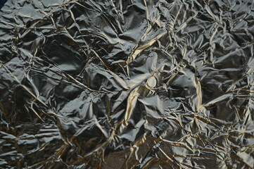 Crumpled black foil texture with gold reflections Perfect for use in luxury design, packaging, product backgrounds, abstract visuals, and digital templates.