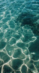 Close up view of shimmering teal water surface with light reflecting off the water, creating a mosaic pattern of light and dark teal shades