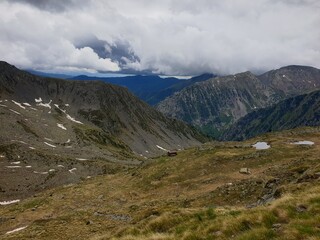 Picturesque landscape on the peak of the mountain with snow and green grass at summer, cloudy in the mountains of Andorra, Arinsal