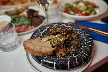 A gourmet dish with bread and fresh, flavorful ingredients elegantly arranged on a plate