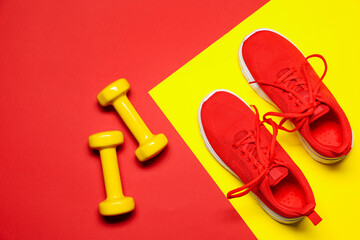 Dumbbells and sneakers on color background, flat lay