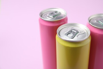 Three tin cans on light pink background, closeup