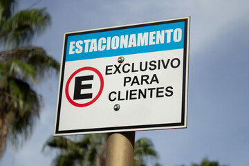 Uma placa na frente de um comércio, escrito estacionameno exclusivo para clientes.