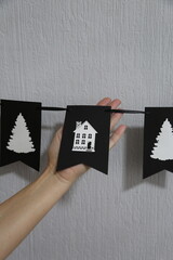 hand holding christmas black flags garland hanging on the wall
