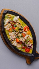Grilled calamari with cherry tomatoes and herbs, served on a hot plate with sauce for an elegant Mediterranean seafood presentation