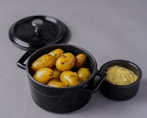 Steaming hot roasted baby potatoes with herbs, in black pot, showcasing rustic and flavorful food presentation