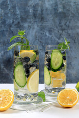 Cold homemade lemonade or cocktail with mint, lemon, cucumber and lime on a sunny table, Detox diet...