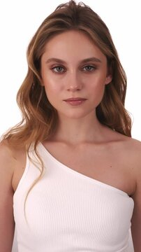 Beautiful woman in white top, blonde hair and neat makeup poses for the camera. Beauty face.