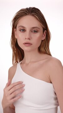Beautiful woman in white top, blonde hair and neat makeup poses for the camera. Beauty face.