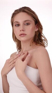 Beautiful woman in white top, blonde hair and neat makeup poses for the camera. Beauty face.