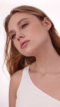 Beautiful woman in white top, blonde hair and neat makeup poses for the camera. Beauty face.