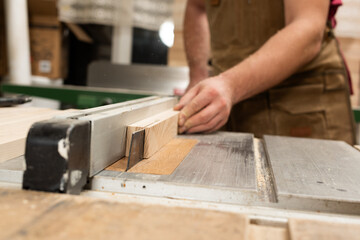 The carpenter saws the bar into thin strips