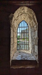 Fototapeta premium An exquisitely crafted stone window, elegantly framed with iron bars, presents a stunning picturesque view outside