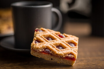 Sweet linzer cake and coffee cup  on wooden table.