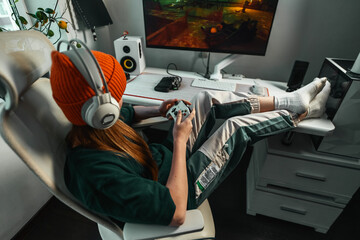 Casual gaming session with girl in cozy home setup. Her concentration on screen and minimalistic room decor highlight gaming as both a hobby and lifestyle. © Aboltin