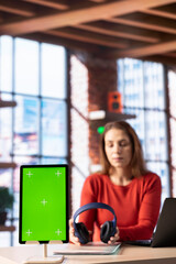 Woman prepares her headset and listen to music while she works next to mockup, helping her focus on...