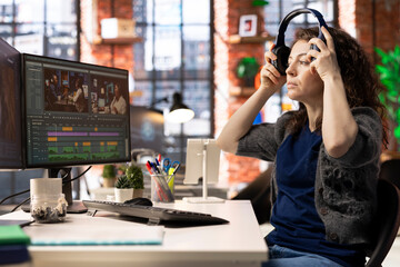 Young woman video editor working with dual monitors in creative agency, editing video footage and does color grading for the creative process. Post production to create content.