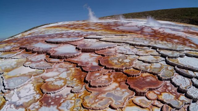 Dallol hydrothermal field shows colorful ponds and mineral formations with steam rising in the air