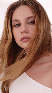 Beautiful woman in white top, blonde hair and neat makeup poses for the camera. Beauty face.