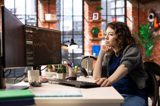 Stock market trader monitors real time charts on a multi screen setup, analyzing index trends and financial growth. Digital platform helps track economic changes and investment opportunities.