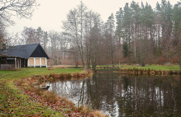 Swedish forest cabin by a reflective pond in the countryside. Black traditional swedish house 