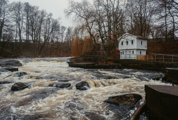 Historic white wooden traditional swedish house cottage by a rushing river in Mörrum, Skåne, Sweden. Countryside in Sweden.