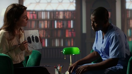 Counselor presents a Rorschach test to a medical assistant in uniform, looking for answers with psychoanalysis illustration. Nurse suffering from PTSD and trauma, interpretation therapy. Camera B.