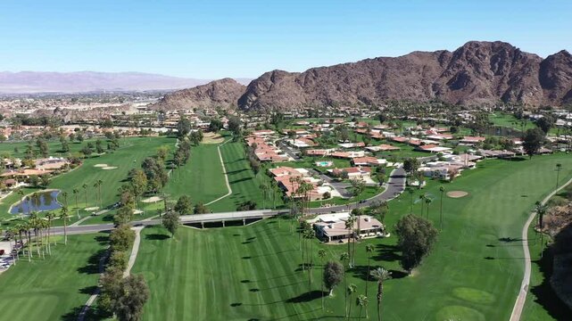 Aerial view of a luxury and upscale neighborhood with a golf course and mountains in the Palm Springs area of California.
