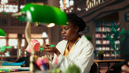 African american students team examining teeth for dentistry thesis, working together on stomatology research in the campus library. Man and woman preparing for their career. Camera B.