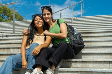 Two female students relaxing on steps outdoors in urban setting