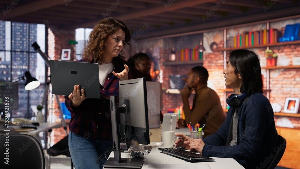 Poster startup intern holding laptop asks questions to senior technician coding advanced ai algorithm. empl