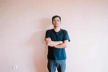 Casual confident asian man with crossed arms posing against plain background