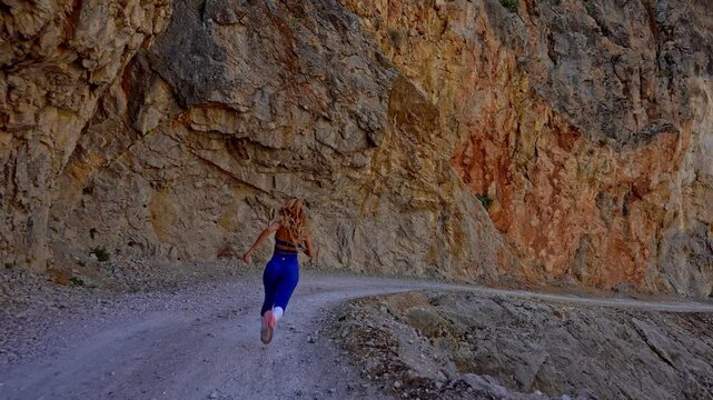 Female Athlete Running Towards Victory on Canyon Path