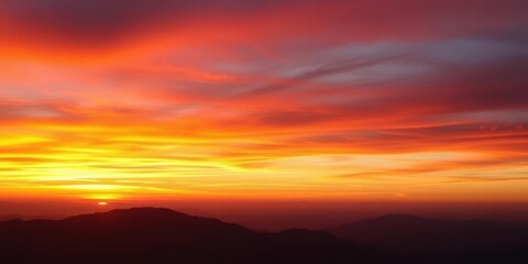 Fiery sunset gradient sky above hazy, indistinct mountain silhouettes, clouds, outdoors