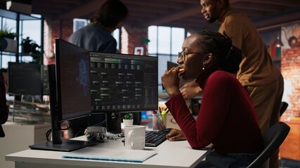 AI startup engineer eating snack while waiting code to finish compiling, annoyed by long wait. Irked software development agency employee consuming food, exasperated by sluggish PC, camera A
