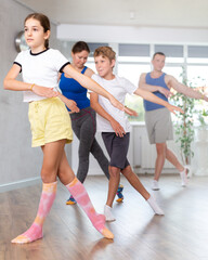 Fototapeta premium Friendly sporty parents with teen daughter and son learning new active dynamic dance in wellness studio. Family health concept