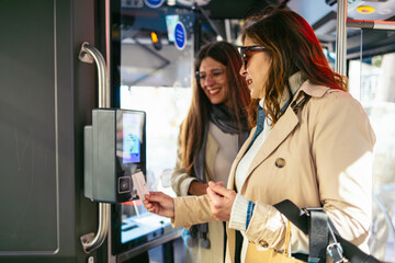 Women using contactless payment entering bus with shopping bags