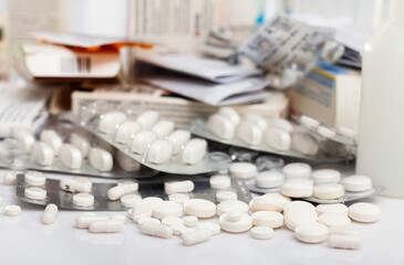 Variety of medicine pills, tablets and capsules scattered on white surface
