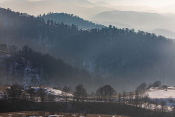 A winter forest landscape in Lori province, Armenia, with misty mountain ridges fading into the...