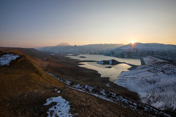 Sunrise above the Yeranos mountain range and Azat Reservoir during a cold winter morning, casting a golden glow over the snow-covered landscape. Great travel and photography destination