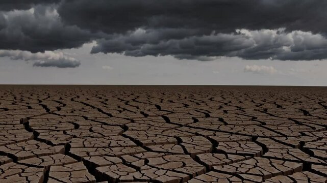 Ominous dark clouds gather over a dry, cracked landscape, hinting at impending rain or a potential storm